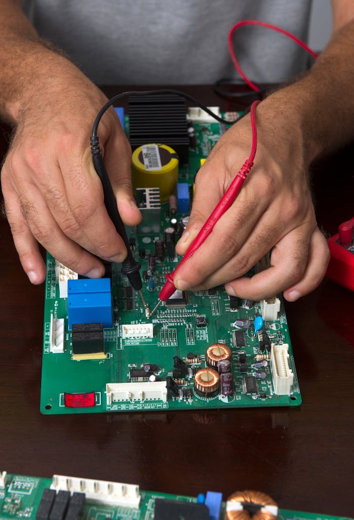 who-we-are Close-up of hands using probes to test a circuit board during electronic repair.