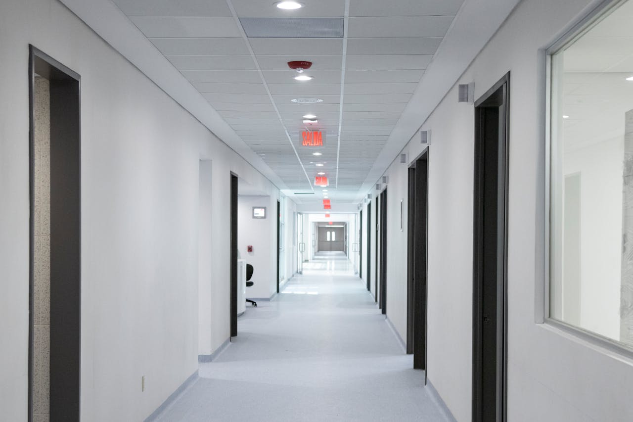White-walled hospital corridor with modern design and bright overhead lighting.